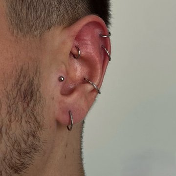 Male ear with conch and mid helix piercings and titanium rings