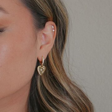 Woman showing healed double helix piercing with gold studs