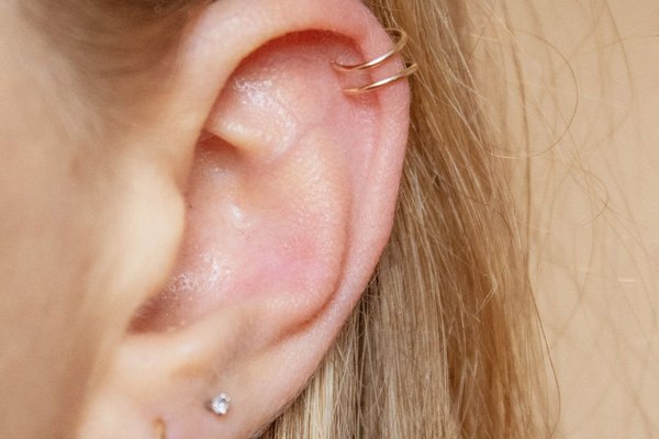 Woman showing healed double helix piercing