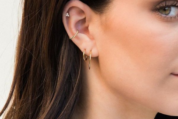 Woman with healed double helix piercing and gold hoops